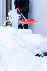 Shovel with snow in man‘s hands, he is cleaning snow in the back yard of his  household, works at winter time outdoors, narrow DOF, soft focus