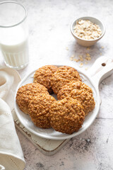 Homemade oat cookies in a plate with a glass of milk, healthy dessert, bright background