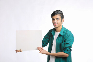 Young Indian man showing blank sing board over white background.