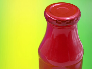 glass bottle with red smoothie isolated on green background, close up with copy space