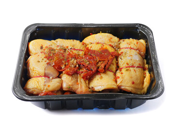 Raw corn fed chicken stuffed thighs wit herbs in a black plastic tray. The product has pronounced yellow color and special taste. Fresh poultry. Meat industry. Butcher craft . Isolated on white.