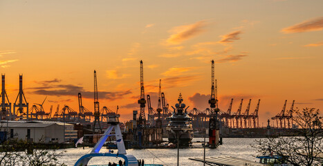 Blick auf den Hamburger Hafen mit Kränen, Werft und Superyacht nach Sonnenuntergang