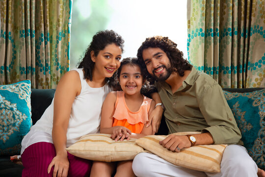 Family Members Posing Together In Front Of Camera While Sitting On Sofa