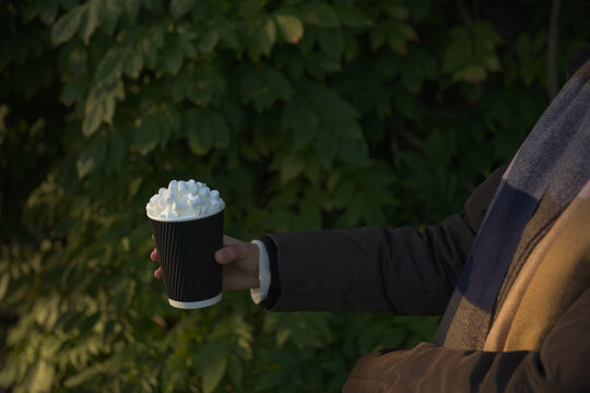 Young Women In Winter Coat And Scarf Holds A Takeaway Beverage. Side On