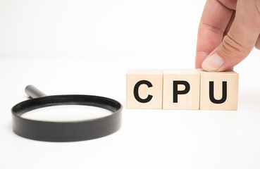 cpu text wooden cube blocks and hand holding magnifying glass on table background.