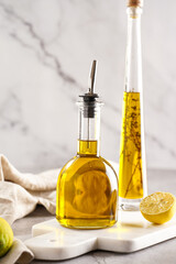 Two bottles with olive oil and fresh herbs - thyme - on white marble background