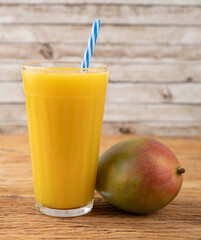 Mango juice in a glass with fruits over wooden table