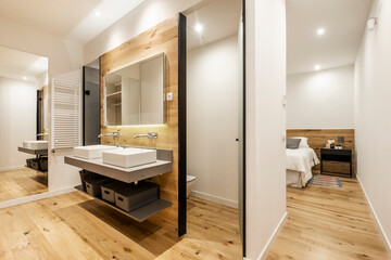 Contemporary decor toilet with two freestanding sinks with frameless mirror in a dressing room of a vacation rental apartment
