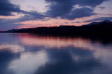 淡い色合いの夜明けの空を湖面に反射する湖。