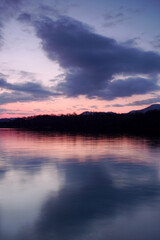 淡い色合いの夜明けの空を湖面に反射する湖。