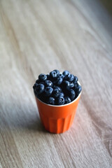 Cup of fresh blueberries on wooden table. Selective focus.