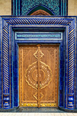 Uzbekistan, beautiful old carved wooden door, encircled with blue ceramics.