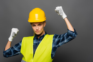 Serious builder in safety vest showing yes gesture isolated on grey