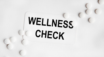 On the business card the text WELLNESS CHECK, next to them are neatly white tablets.