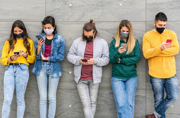 Fototapeta premium Group of young millennials on the grey wall with face mask looking their smartphone - Friends after the lockdown for protection by Corona Virus, Covid-19 on the social network - Copy space