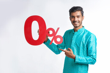 Indian man holding zero percent sign board promoting offers on festival season while wearing traditional cloths, standing over white background.