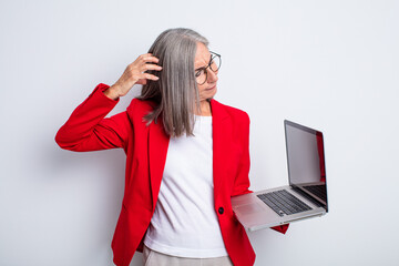 senior pretty woman feeling puzzled and confused, scratching head. business and laptop concept