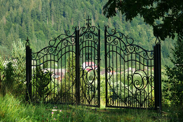 Metal gate with a cross at the top, entrance to the local church in Carpathians - obrazy, fototapety, plakaty