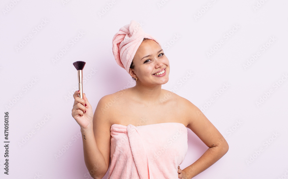 Wall mural hispanic pretty woman smiling happily with a hand on hip and confident. make up brush concept