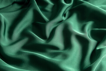 Fototapeta premium Closeup of stylish green silk waves.Preparation fabric for sewing evening garment.