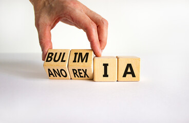 Bulimia or anorexia symbol. Doctor turns wooden cubes and changes the word anorexia to bulimia. Beautiful white table, white background, copy space. Medical, bulimia or anorexia concept.