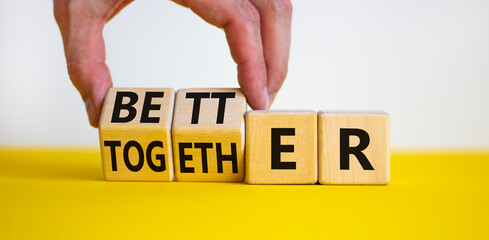 Better together symbol. Businessman turns cubes and changes the word together to better. Beautiful yellow table, white background, copy space. Business, motivational and better together concept.