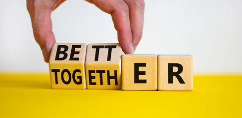 Foto op Plexiglas Better together symbol. Businessman turns cubes and changes the word together to better. Beautiful yellow table, white background, copy space. Business, motivational and better together concept. © Dzmitry