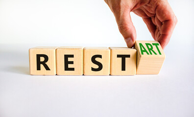 Rest and restart symbol. Businessman turns a wooden cube and changes the word rest to restart. Beautiful white table, white background, copy space. Business, rest and restart concept.