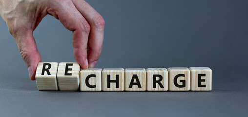 Charge or recharge symbol. Businessman turns wooden cubes and changes the word 'charge' to...