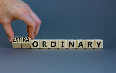 Ordinary or extraordinary symbol. Businessman turnes wooden cubes and changes words 'Ordinary...