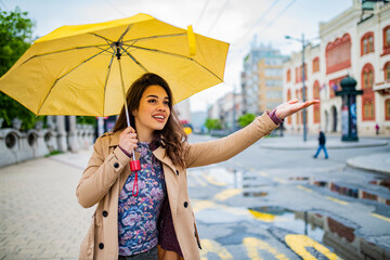 Rainy day asian woman wearing a raincoat outdoors. She is happy.She used her hand to touch the...