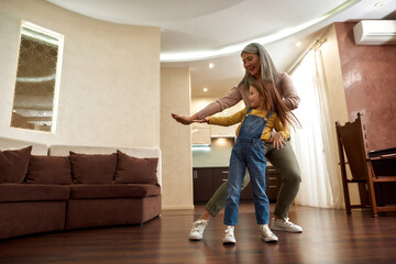 Tireless energetic mature woman dancing with cute girl