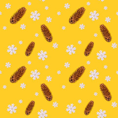 Seamless yellow background with Christmas decorations, white snowflakes, fir cones and a red wooden Christmas tree