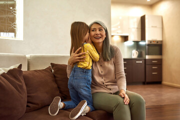Little girl discretely telling granny her secret