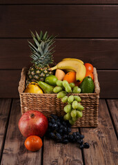 Mix of fresh juicy colorful exotic tropical fruits in basket on wooden background