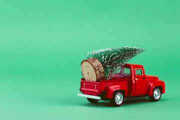 Red toy car carrying Christmas tree.