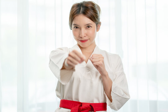Portrait of woman in Taekwondo clothes show fighting pounch on white background .