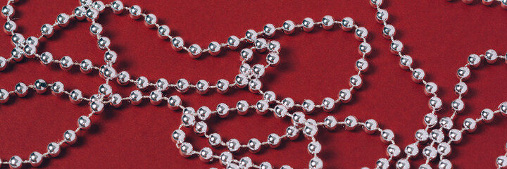 Banner. Silver holiday decorations on a red background. Backdrop for your festive ideas. Minimalistic style. Layout for the holiday. Top view, flat lay