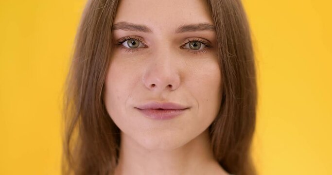 Natural beauty. Close up portrait of young pretty peaceful caucasian woman looking at camera, yellow studio background