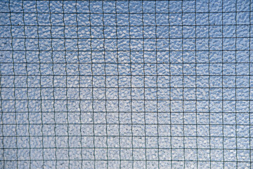 Close up of frosted safety glass against a blue sky