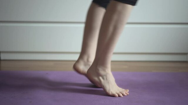 Woman doing yoga exercises at home. Close-up. Warm-up exercise for feet and legs. Sport concept. Home fitness. 