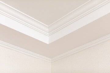 Fototapeta premium Close-up detail of decoration in interior renovation. Angular ceiling skirting made of classic white moldings.