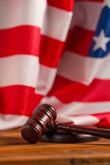 Wooden judge gavel and soundboard on american flag background.