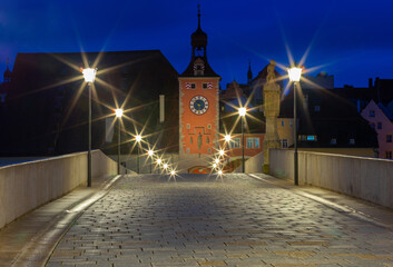 Regensburg. Old stone bridge over the Danube river in the night light.