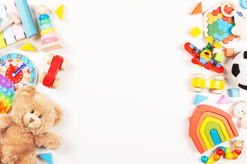 Baby kids toys frame on white background. Teddy bear and many colorful educational wooden, plastic toys. Top view, flat lay