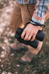 Woman is standing with binoculars in her hand. Top-down view. Selective focus on binoculars.