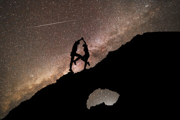 The copuple dancing on the clif in the starry night with brigt milky way galaxy. Silhouettes in the...