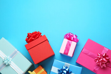 Many colorful gift boxes on light blue background, flat lay. Space for text
