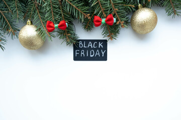 Black Friday big sale promotional sign on white background with fir branches, bows and Christmas balls. Special discount offer. Advertising message. Holiday shopping. Top view, copy space for text