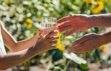 The child and the father are drinking and giving water in a glass. Selective focus. © yanadjan